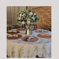 Mesa redonda posta com arranjo floral para recepção de casamento